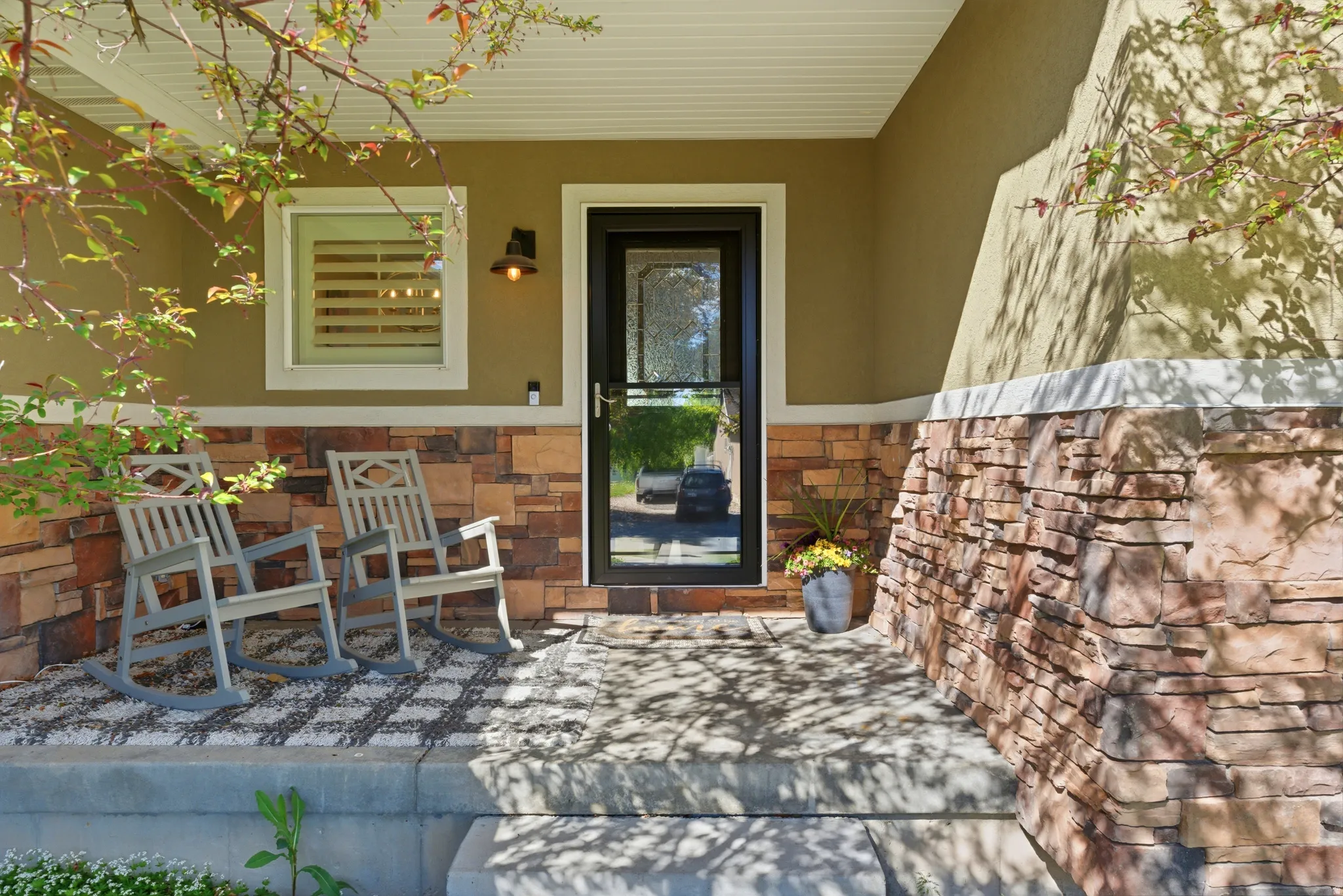 Covered porch entry featuring a stone veneer facade and stucco siding