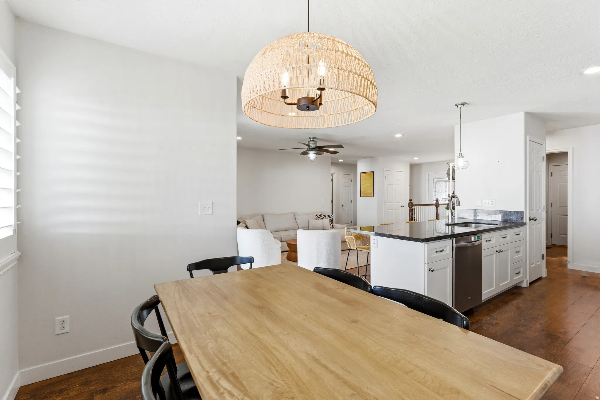 Open-concept dining area featuring a natural wood dining table and a woven pendant light fixture