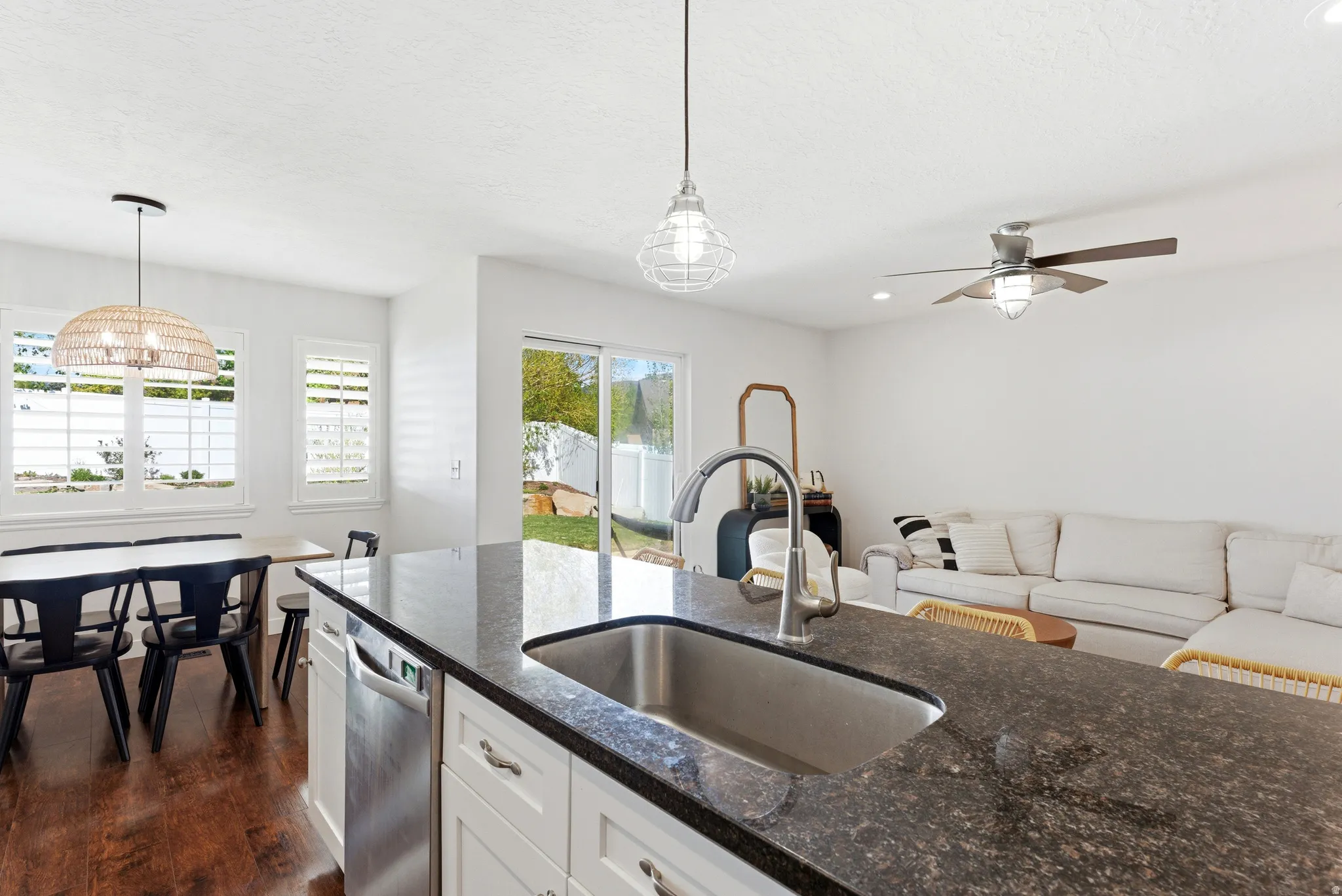 Kitchen island featuring a stainless steel undermount sink and dark granite countertop