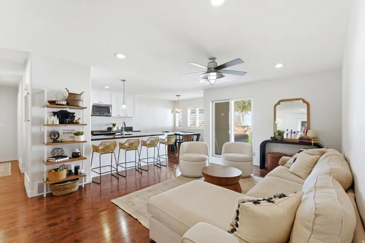 Expansive open-concept living area featuring rich wood-finish flooring, recessed lighting, and a modern ceiling fan