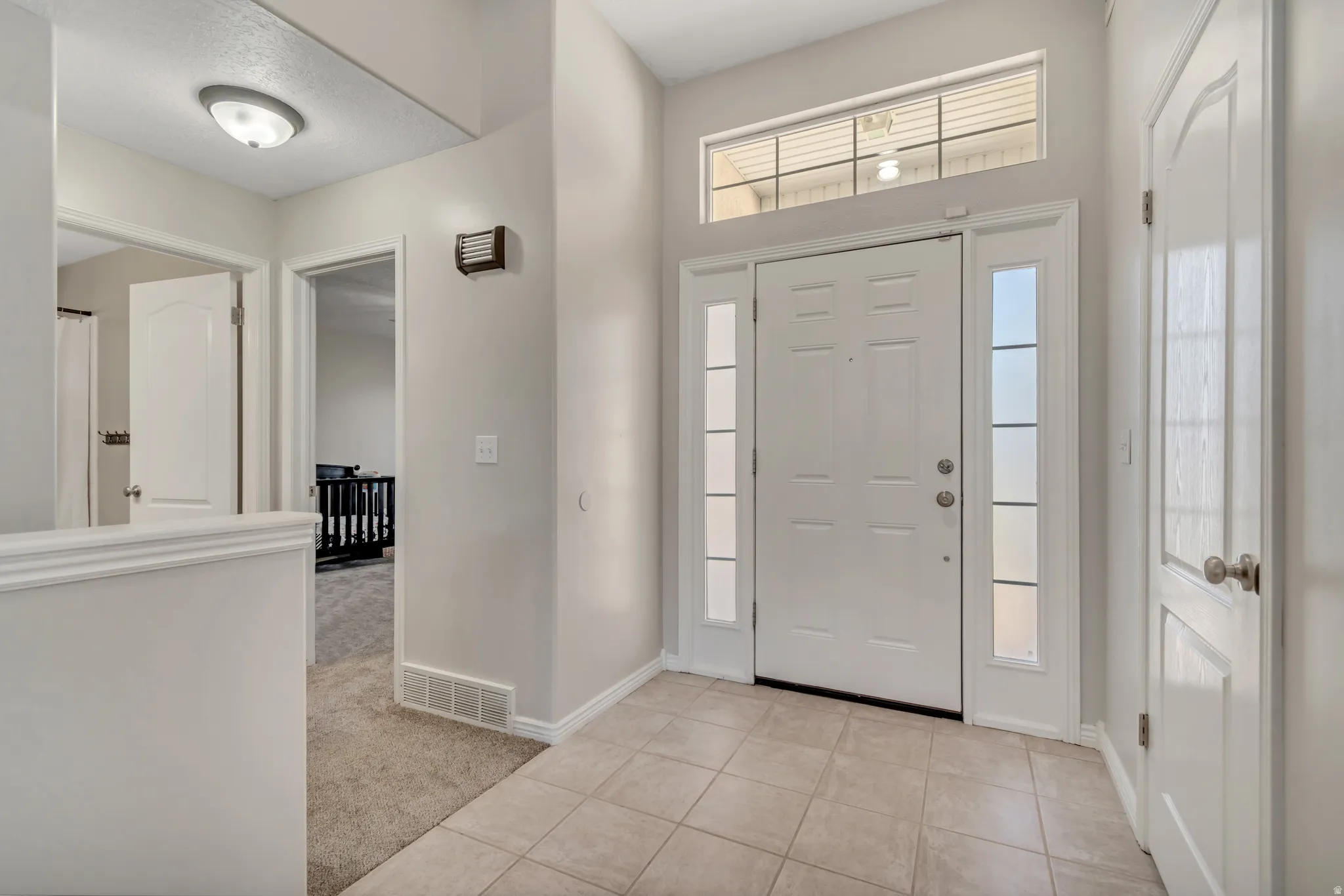 Foyer entrance with tile flooring, a transom window, and two sidelights