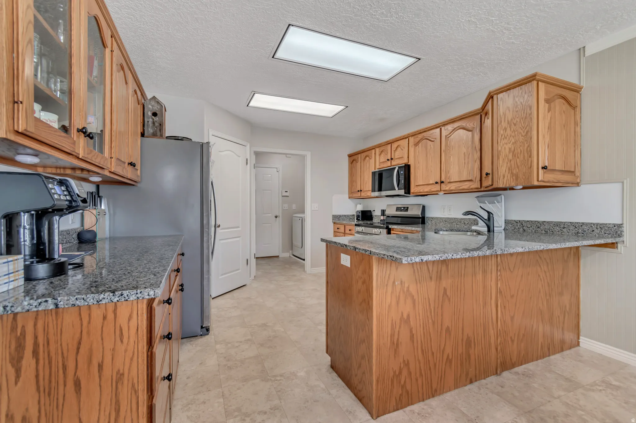 Kitchen featuring wood cabinetry, stone-finish countertops, and tile flooring