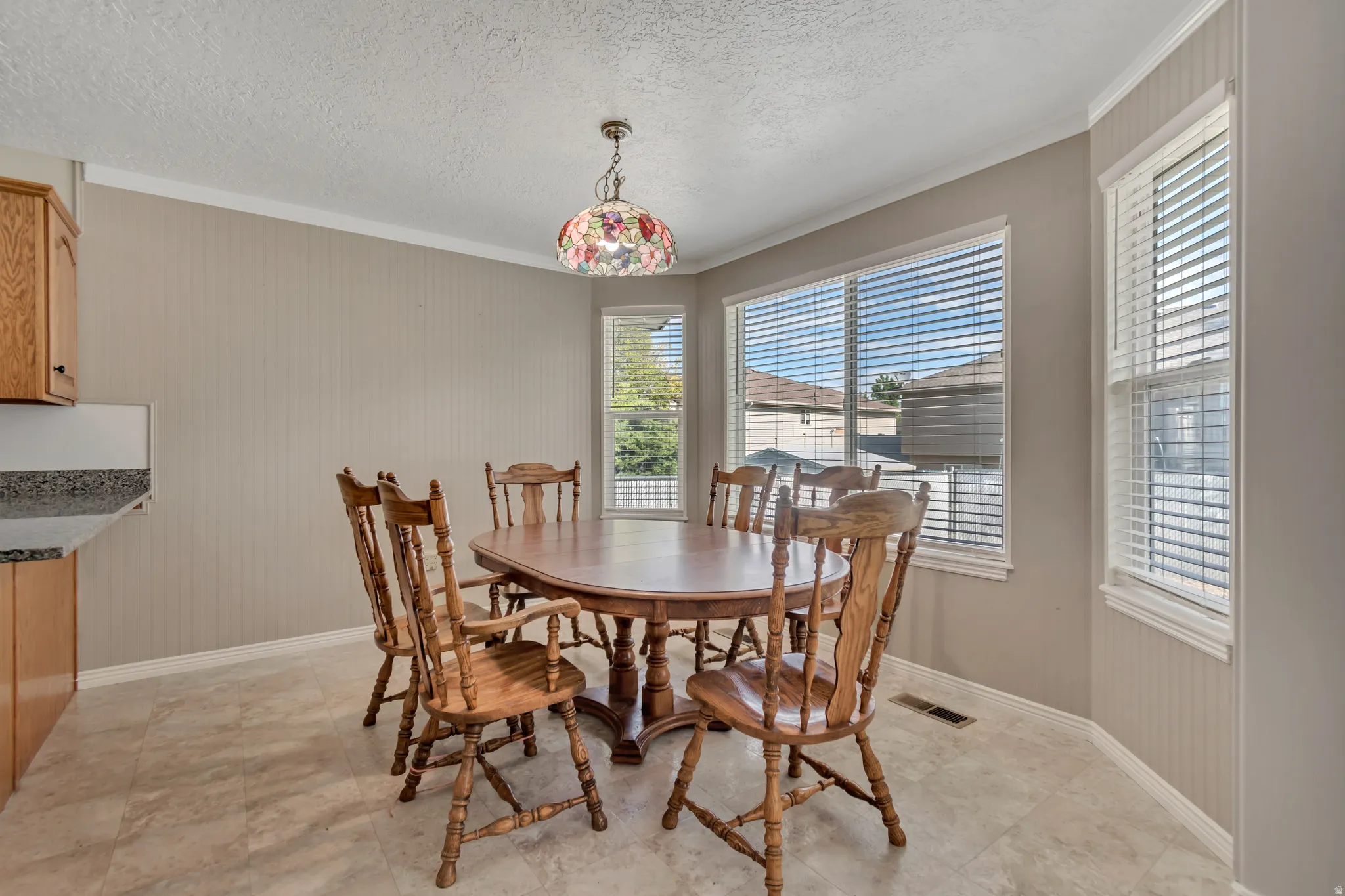 Dining area featuring a bay window with multiple panes, crown molding, and tiled flooring