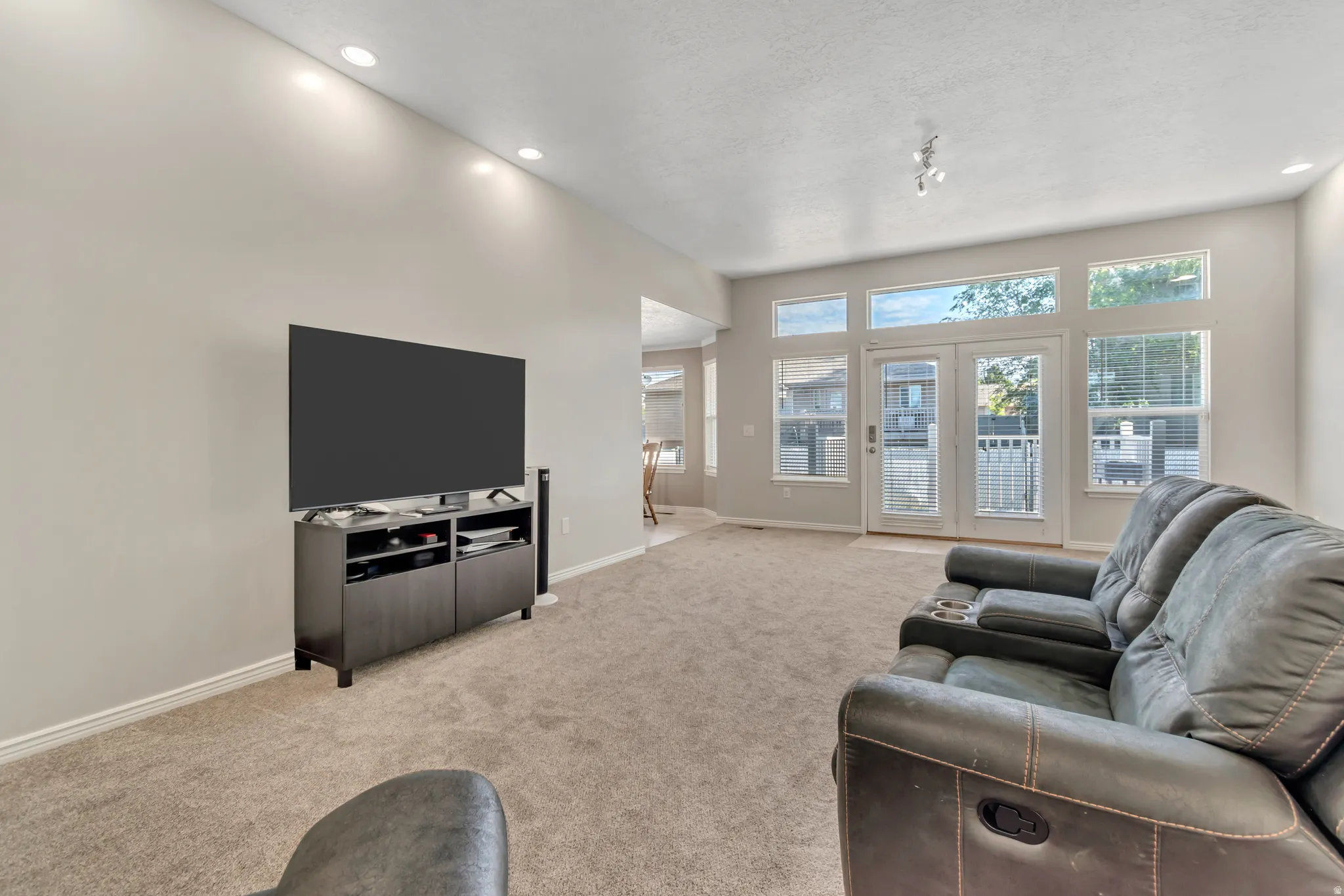 Carpeted living area featuring recessed ceiling lighting and a bank of windows with French doors