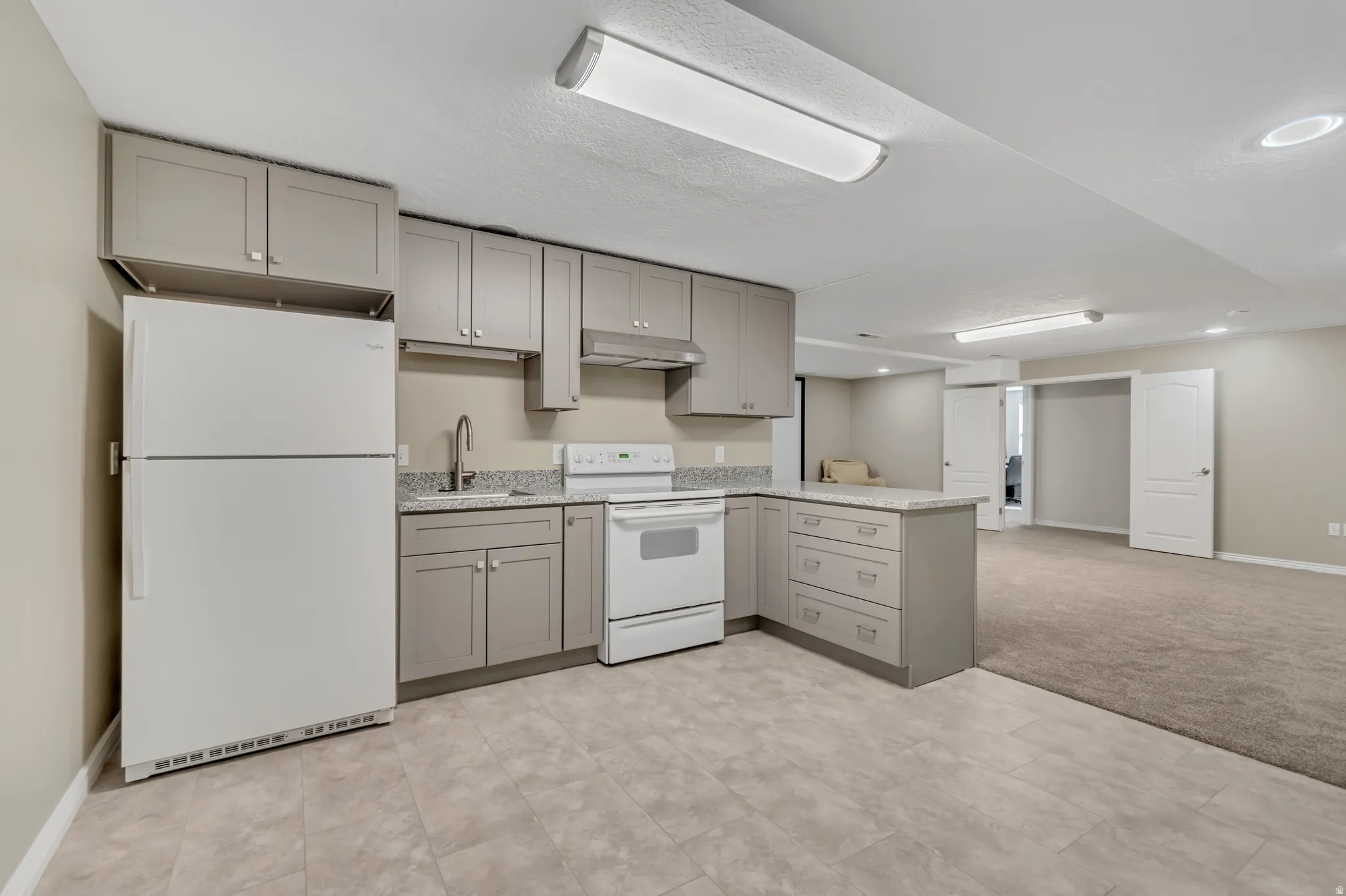 Kitchenette featuring light gray cabinetry, a white refrigerator, and a white electric range with matching hood