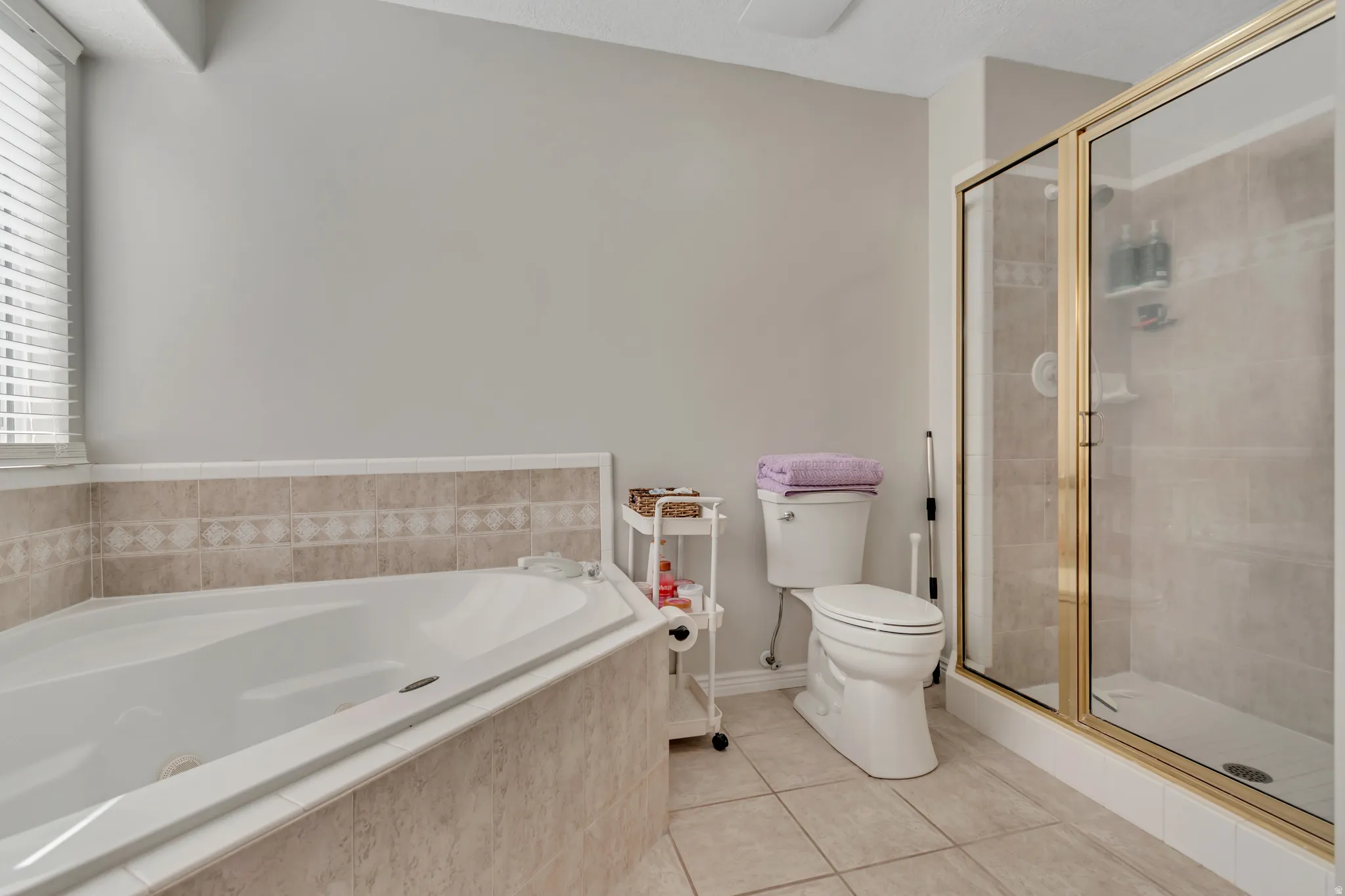 Corner soaking tub with tiled surround featuring a decorative accent band