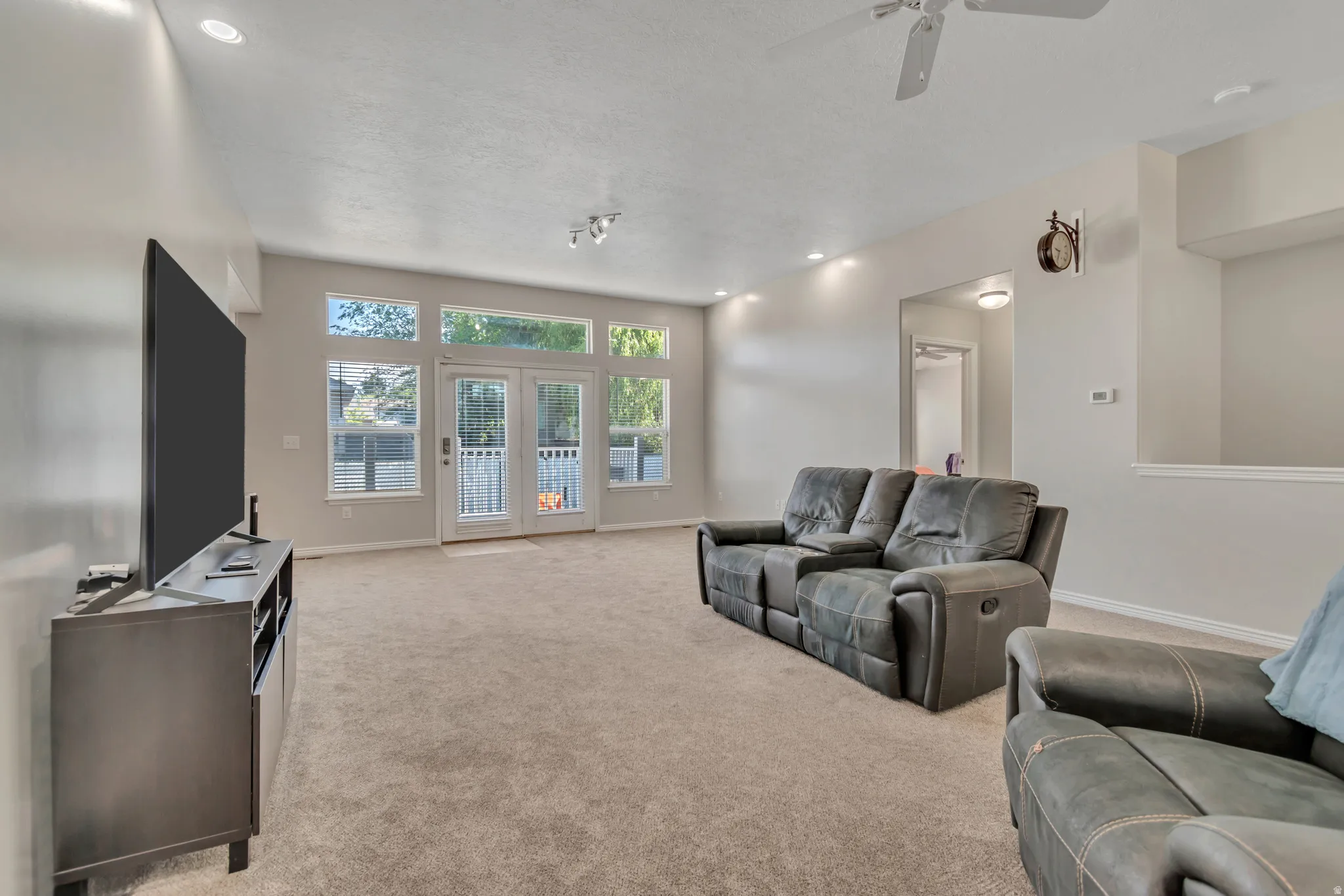 Open-concept living area with neutral carpeting and light-toned walls