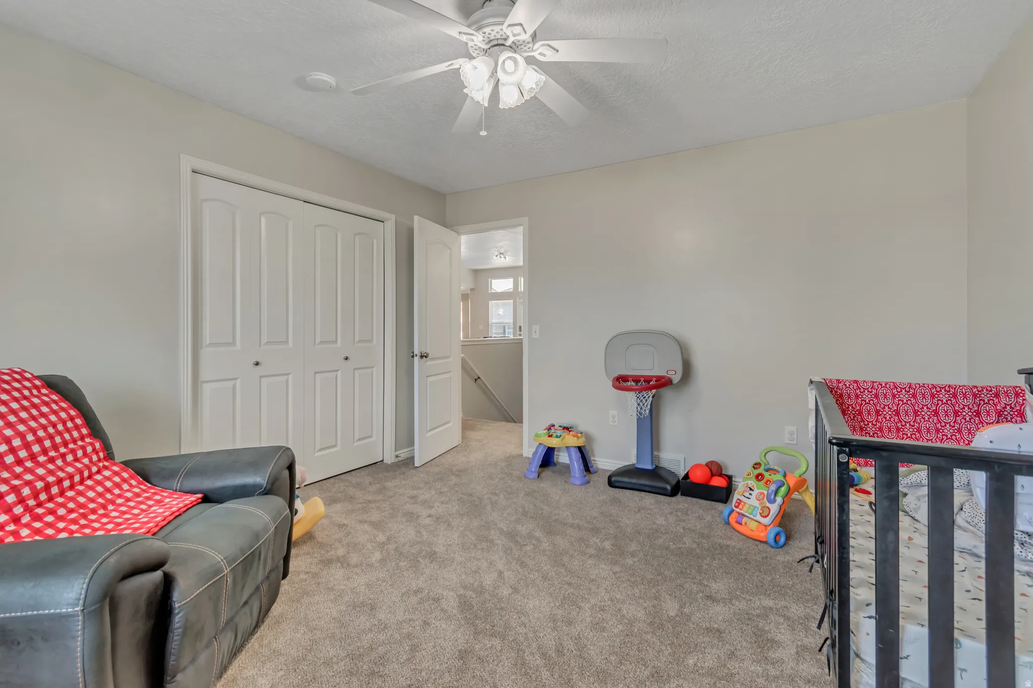 Carpeted room featuring a ceiling fan with light fixture, light gray wall paint, and a bifold closet door
