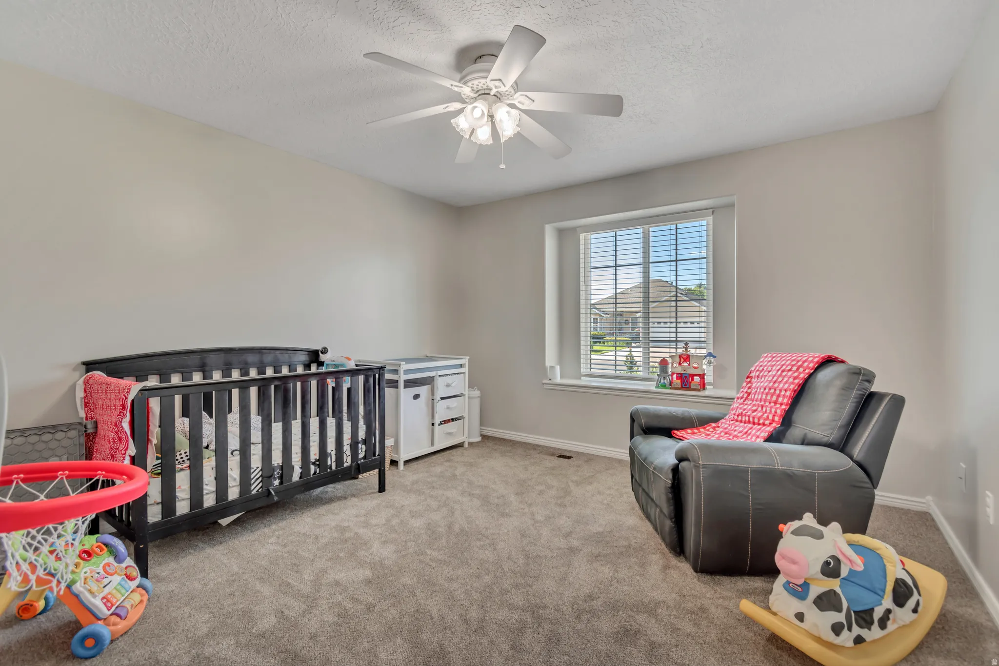 Carpeted room with a ceiling fan, light gray walls, and a window featuring horizontal blinds
