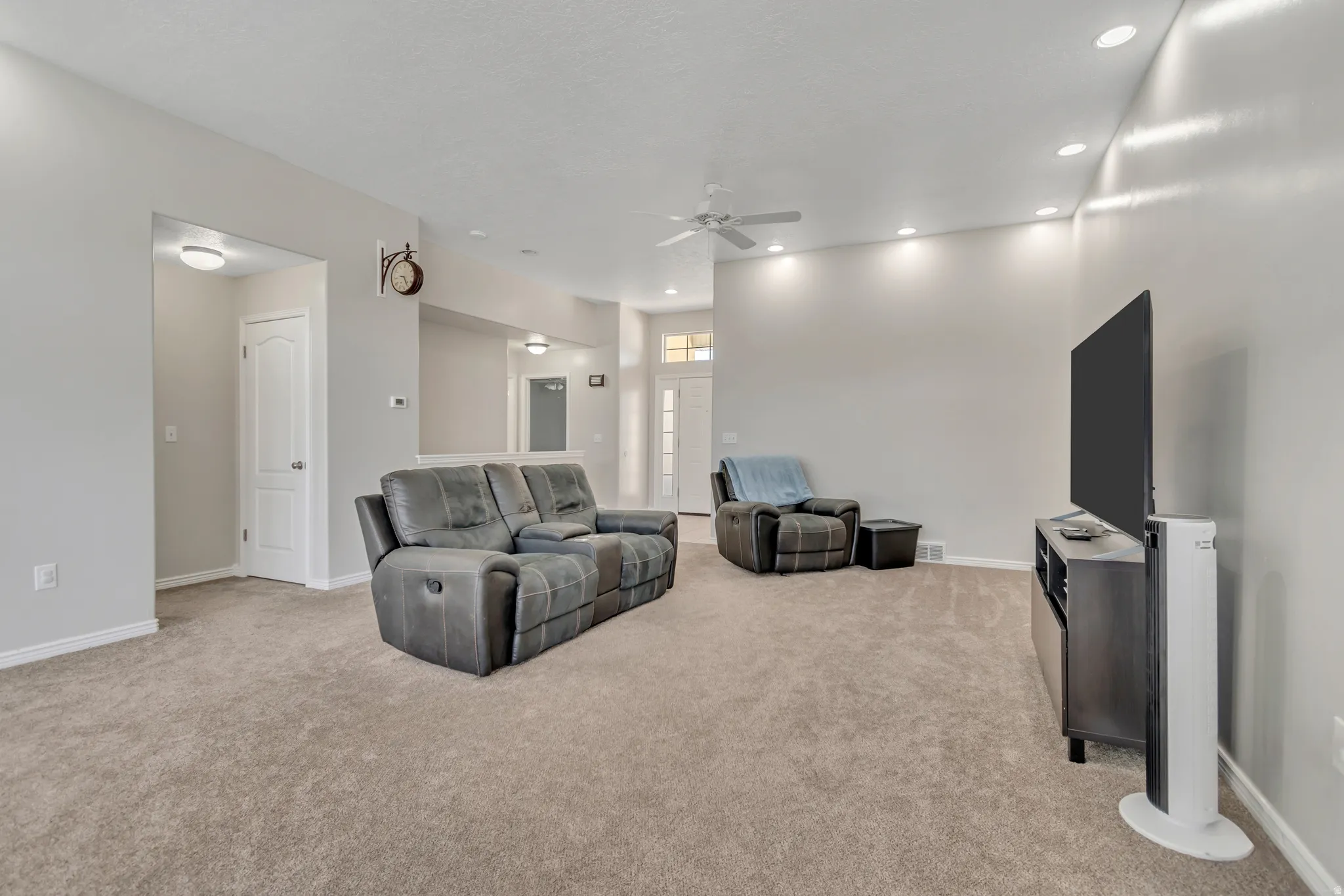 Spacious living area featuring neutral carpeting, recessed ceiling lighting, a ceiling fan, and light gray wall finishes