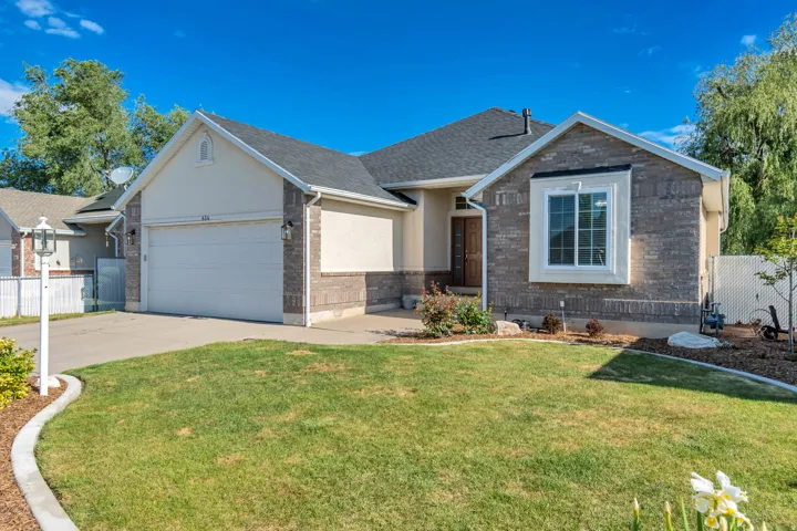 Single-story residence featuring a two-car garage, brick and stucco exterior, a dark shingle roof, and a mature front lawn with established landscaping