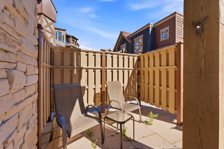 Private patio featuring stone veneer wall and wood fence enclosure