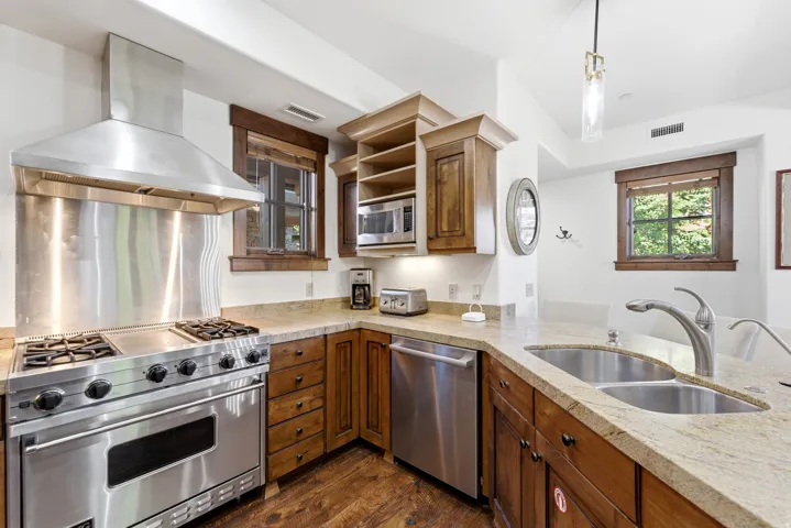 Kitchen featuring a stainless steel range with griddle, coordinating range hood, and double basin sink