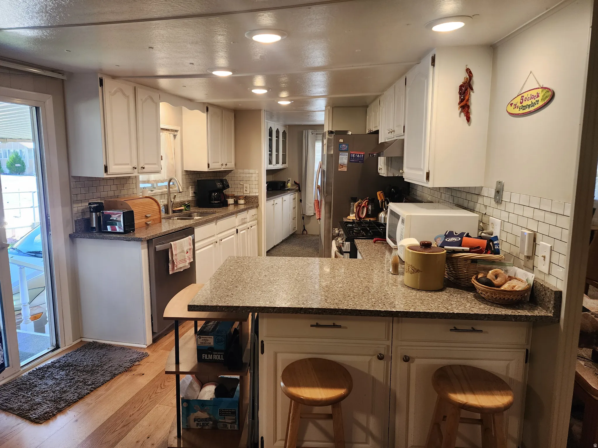 Kitchen featuring white cabinetry, granite-style countertops, subway tile backsplash, recessed lighting, and wood-finish flooring