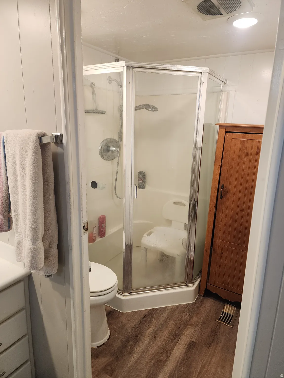 Corner glass shower enclosure with chrome fixtures