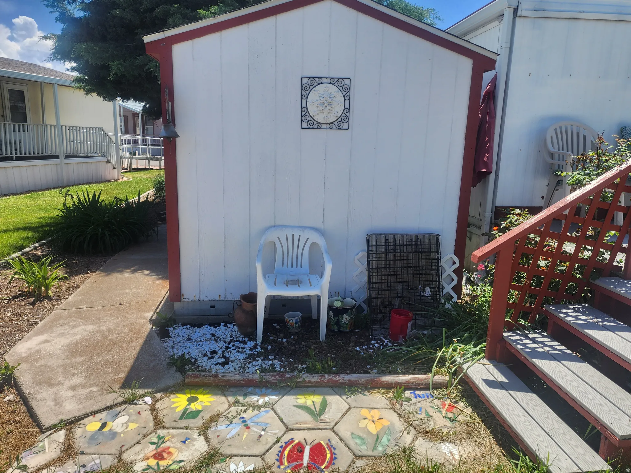 Detached storage shed with white siding and red trim