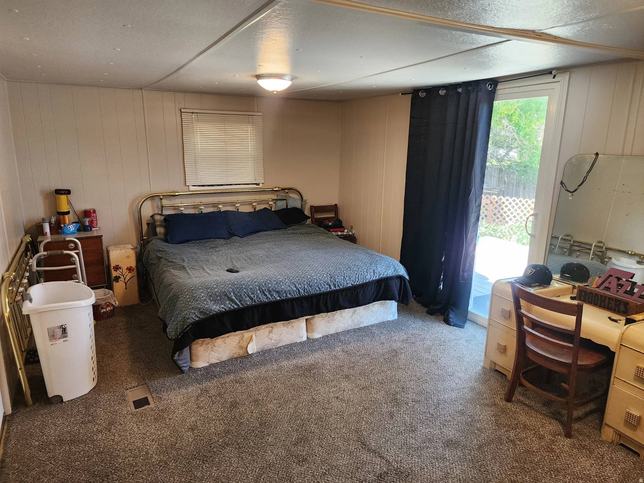 Bedroom with sliding glass door access to the exterior, light gray paneled walls, and carpet flooring