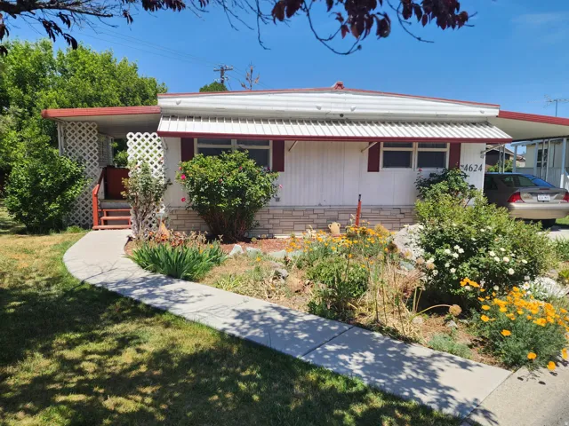 White siding residence featuring red window awnings and a red roof trim