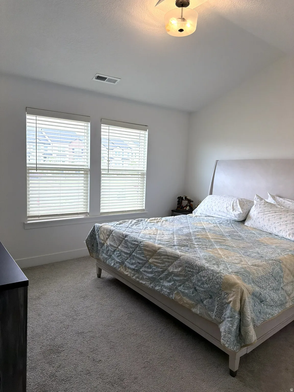 Room featuring two windows with blinds, light gray wall paint, and gray carpet flooring