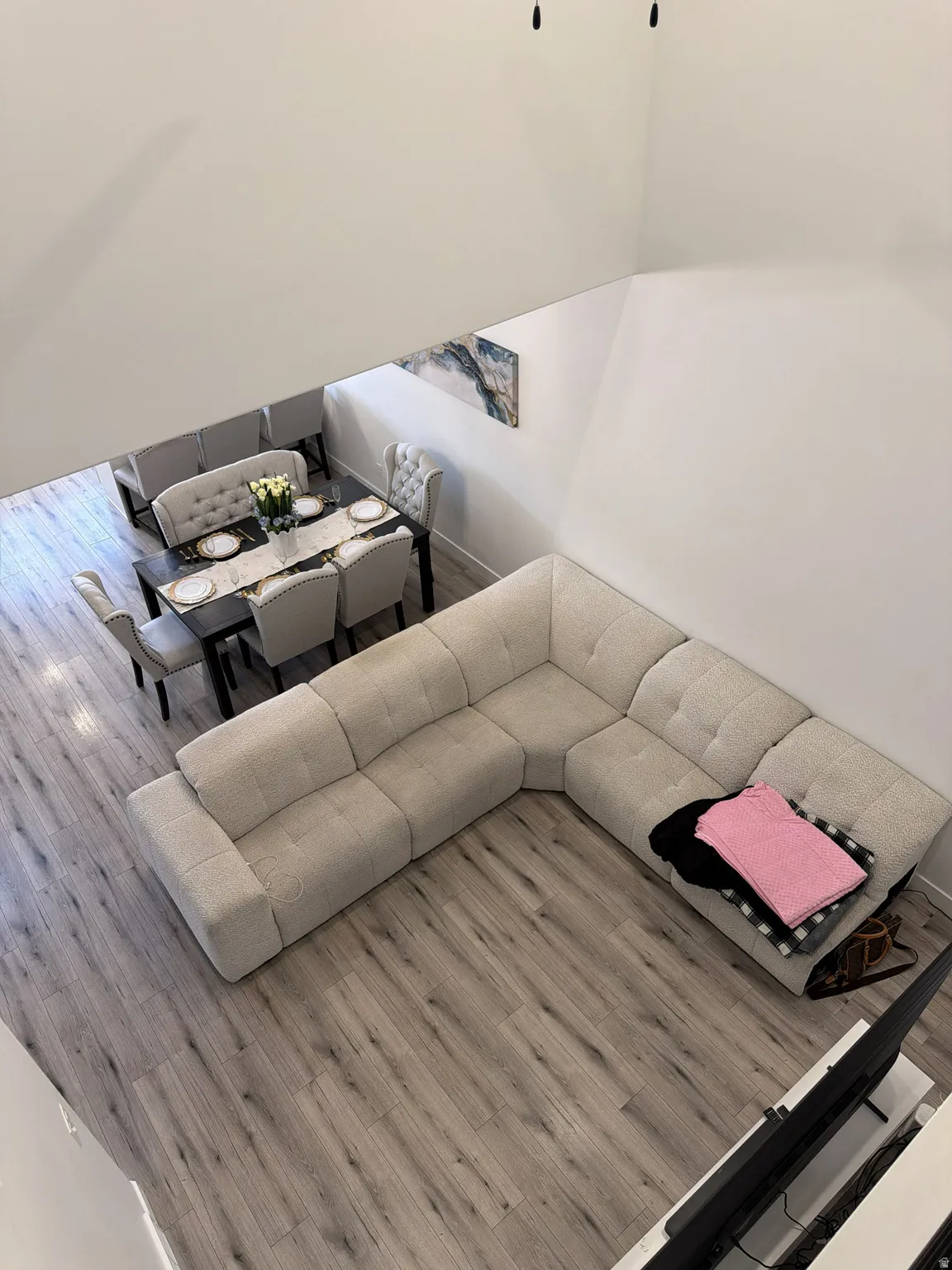 Open-concept living area featuring light wood-finish flooring, a dining area with a dark table, and white walls