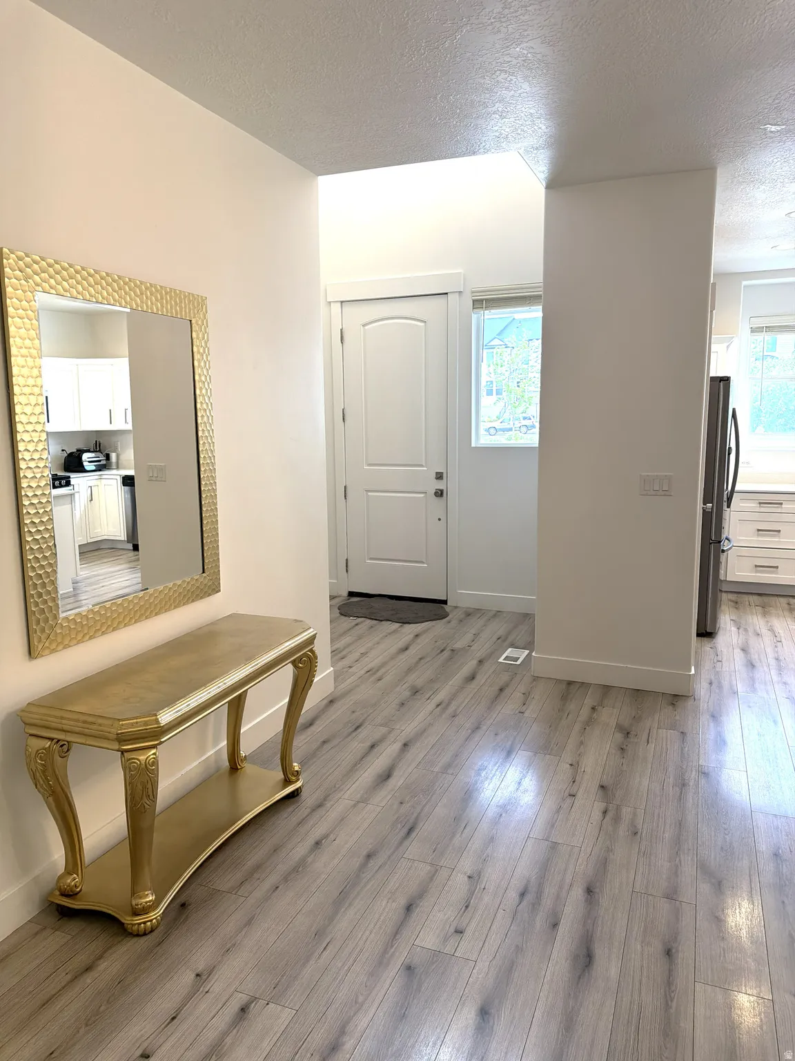 Entryway featuring wood-finish flooring, white trim, and a white arched panel door
