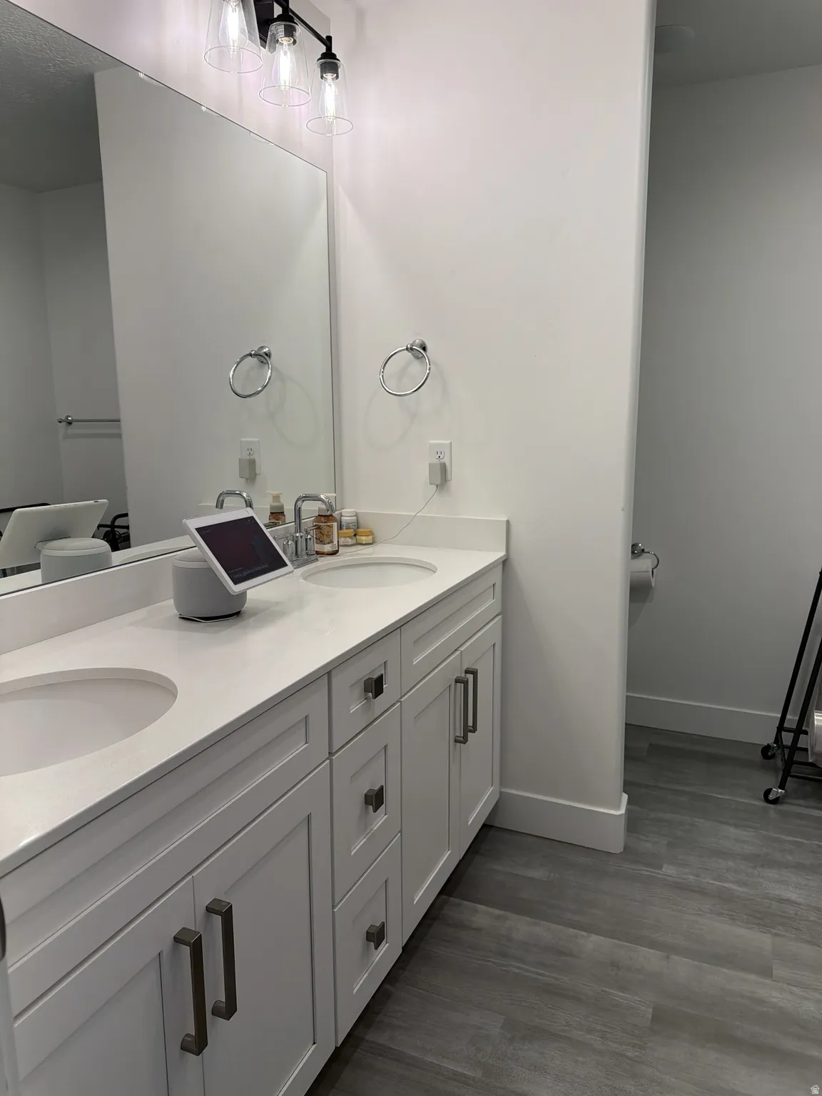 Dual vanity with integrated sinks, white cabinetry, and gray wood-finish flooring