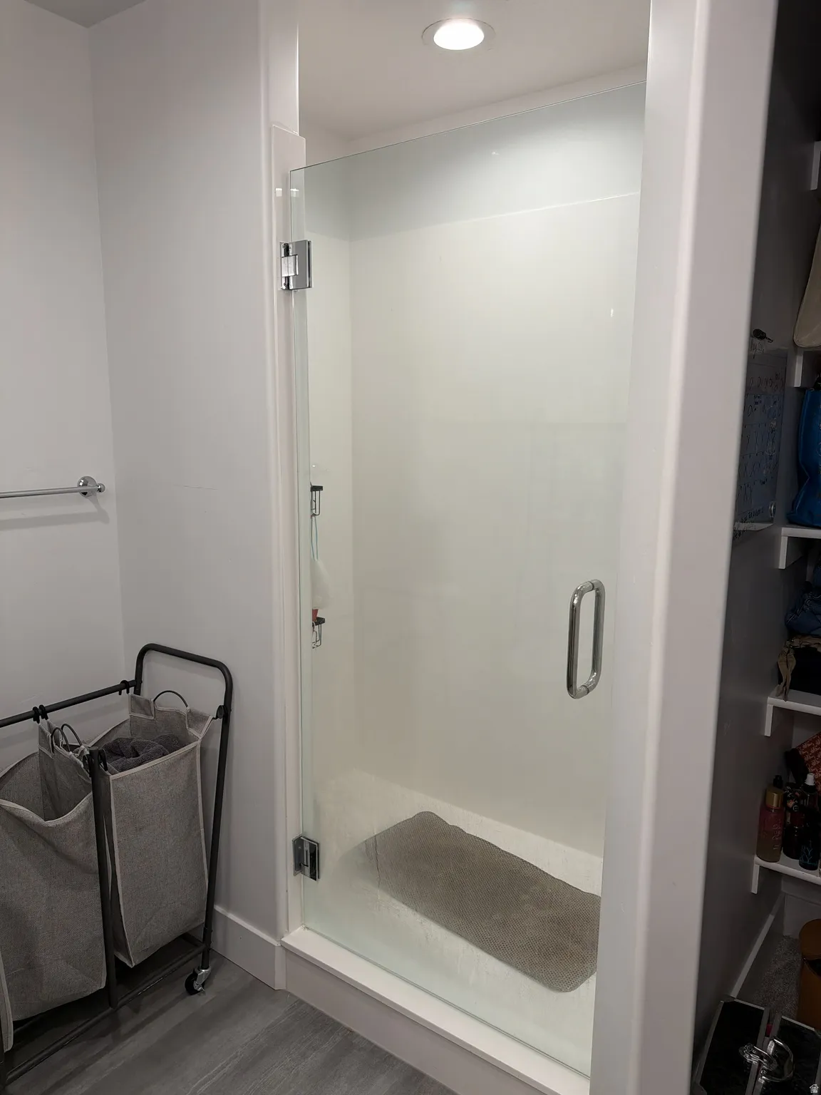 Glass-enclosed shower with a bright white surround and recessed ceiling lighting