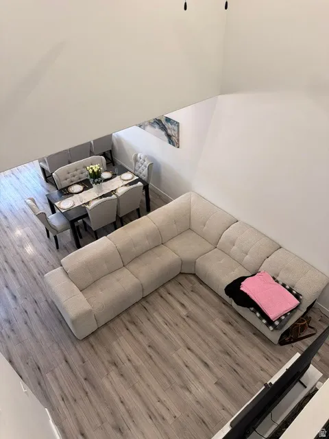 Open-concept living space featuring high ceilings, wood-finish flooring, and crisp white walls
