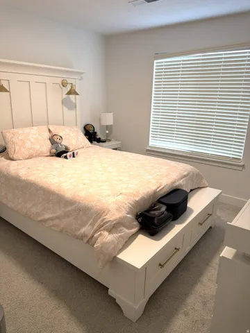 Bedroom featuring neutral carpeting, a window with blinds, and white walls