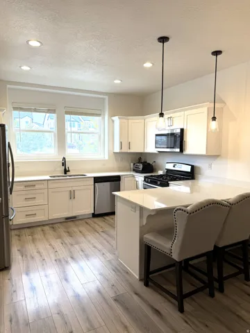 Modern kitchen featuring light wood-finish flooring, white cabinetry, and a central island with a breakfast bar