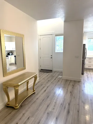 Entryway featuring wood-finish flooring, white trim, and a white arched panel door
