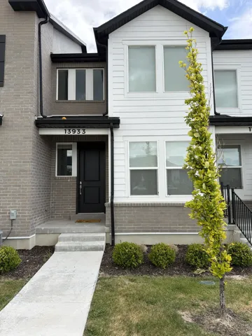 Contemporary townhome facade featuring white horizontal siding and light gray brick accents