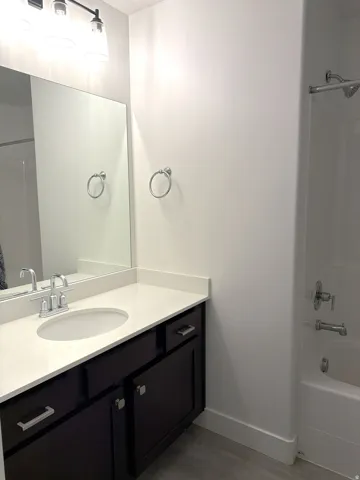 Vanity featuring a white countertop with an integrated sink and chrome faucet
