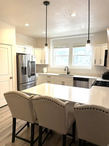 Kitchen featuring a center island with a light-toned countertop, stainless steel appliances, white cabinetry, and recessed lighting