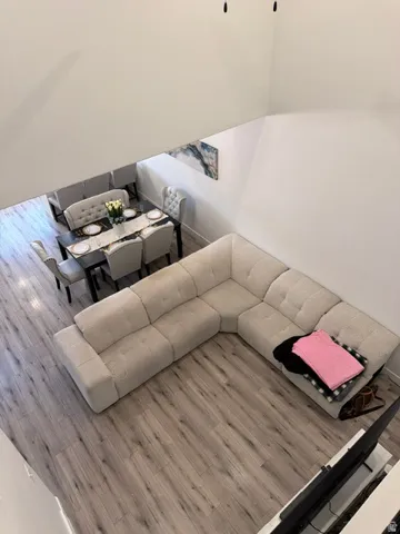 Open-concept living space featuring high ceilings, wood-finish flooring, and crisp white walls