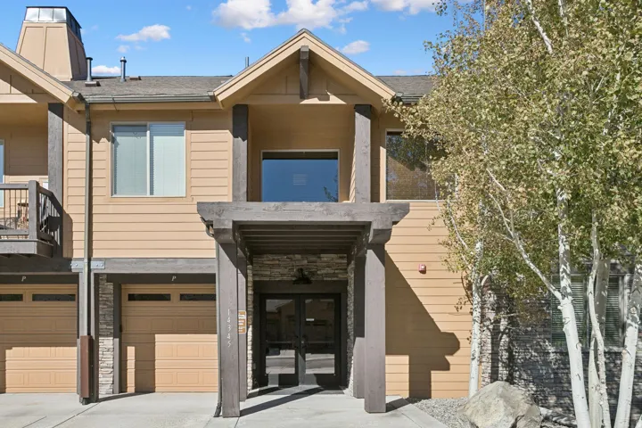 Multi-level building with tan horizontal siding and stacked stone accents