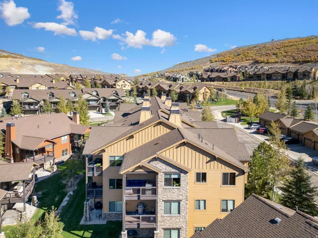 Multi-story residential building featuring balconies, stone and siding exterior finishes, and a dark shingle roof