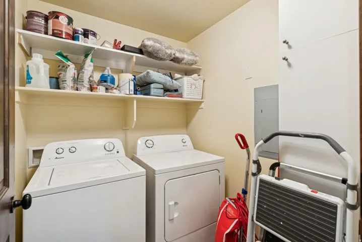 Dedicated laundry area featuring a washer and dryer, integrated shelving, and a built-in storage cabinet