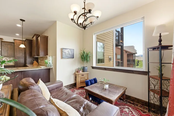 Open-concept living space featuring a warm color palette, overhead chandelier, and a large window