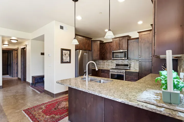 Kitchen featuring granite countertops, dark wood cabinetry, stainless steel appliances, a tiled backsplash, and recessed lighting