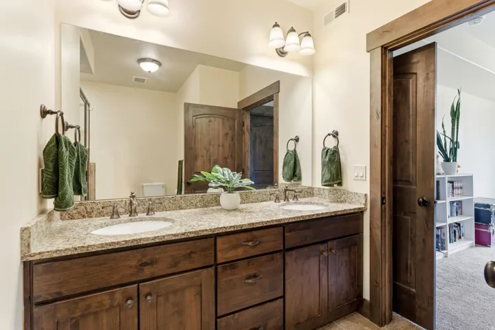 Dual vanity with granite-style countertop, undermount sinks, and dark wood-finish cabinetry