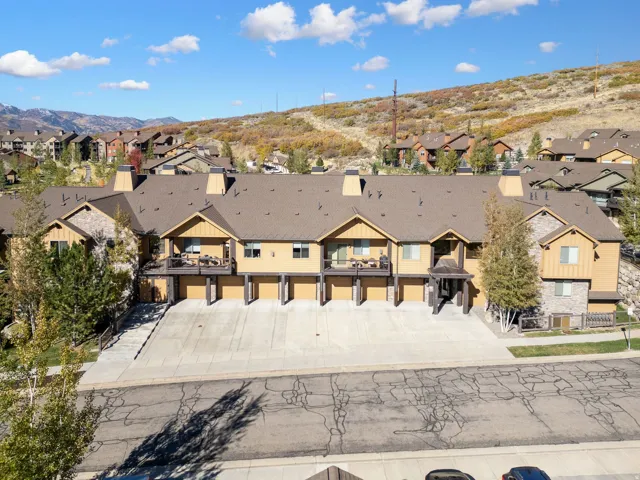 Multi-level townhome architecture featuring gabled roofs, stone veneer, and wood siding