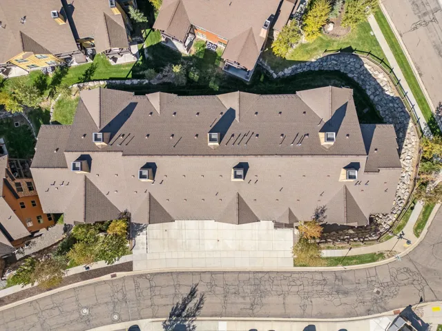 Multi-unit residential structure featuring a brown shingle roof, multiple dormer windows, and varied rooflines
