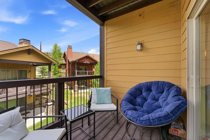 Private balcony featuring wood-finish decking, dark metal railings, and a yellow siding exterior