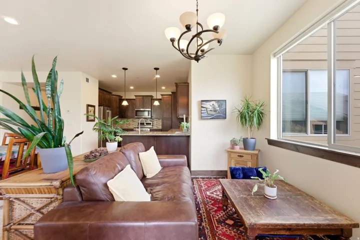 Open-concept living area featuring a kitchen with dark wood-finish cabinetry, stainless steel appliances, and a tile backsplash