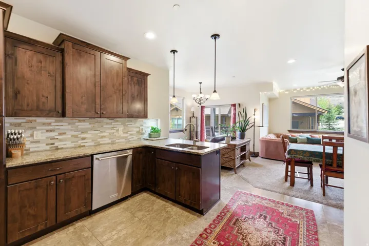 Kitchen featuring rich wood cabinetry, granite countertops, a mosaic tile backsplash, and stainless steel appliances