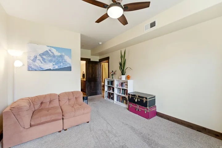 Carpeted room featuring a ceiling fan with integrated lighting, recessed wall paneling, and baseboard trim