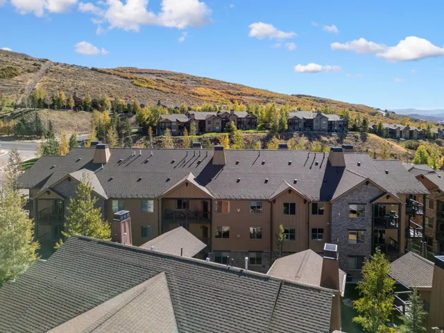 Multi-story building featuring a pitched shingle roof, stone and wood-paneled exterior, multiple private balconies, and prominent chimneys