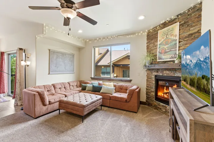Living area featuring a stone-clad fireplace with a wood mantel, a large window offering natural light, and recessed ceiling lighting