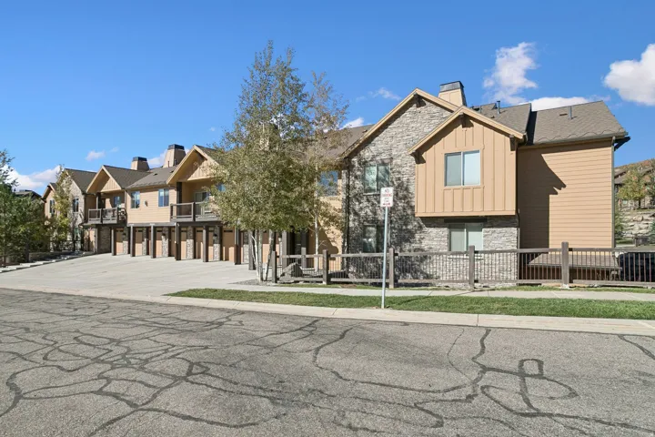 Multi-level townhome-style residences featuring stone and siding exteriors, private balconies, and dedicated garage parking
